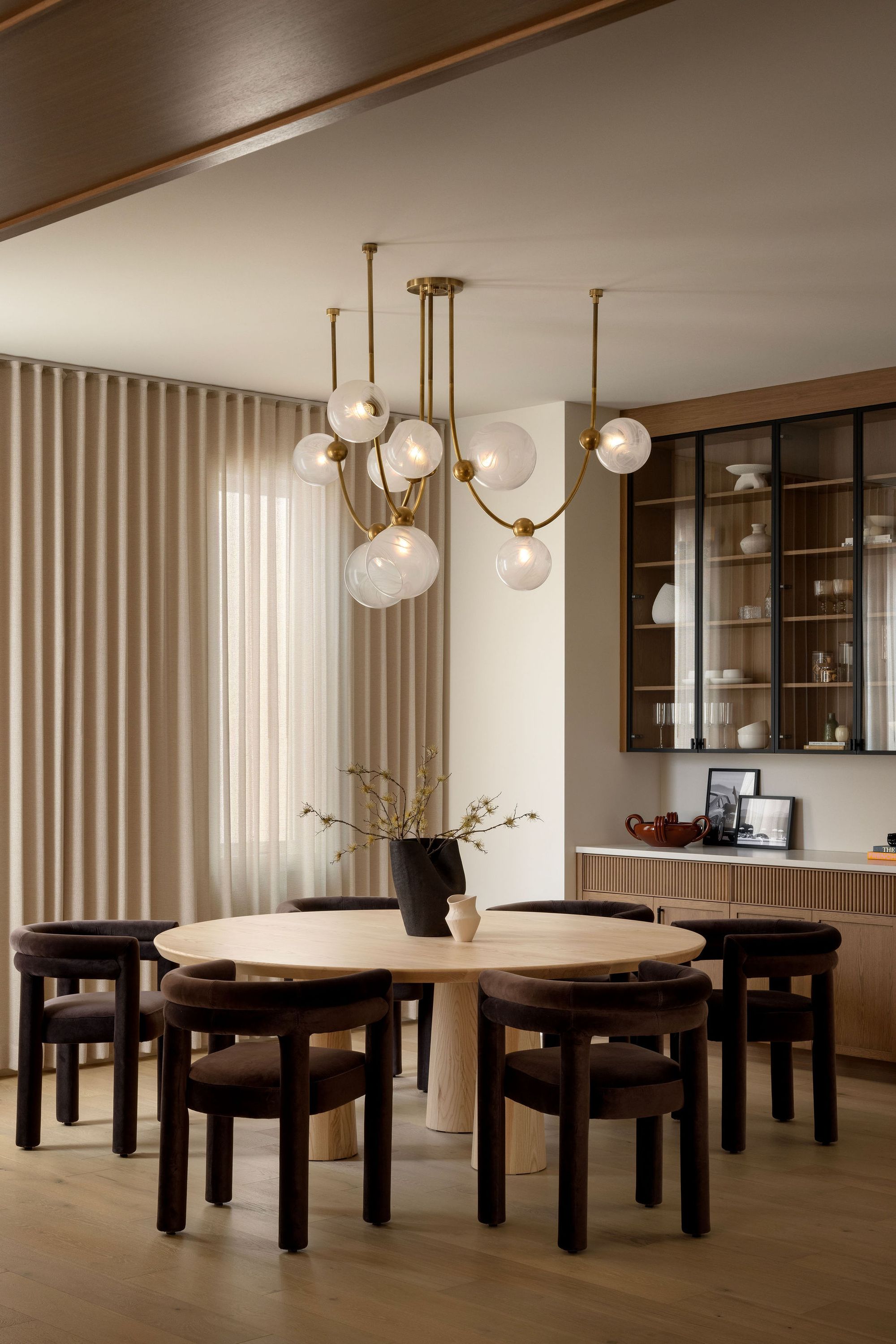 Dining room with round table and brass chandelier in The Charlotte home