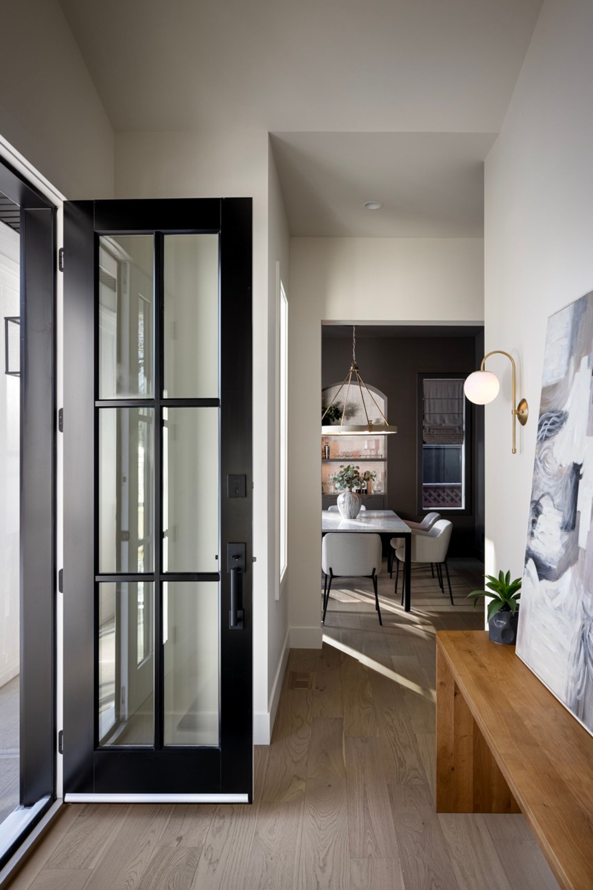 Front entry with black glass door and bench in the Riverdale home