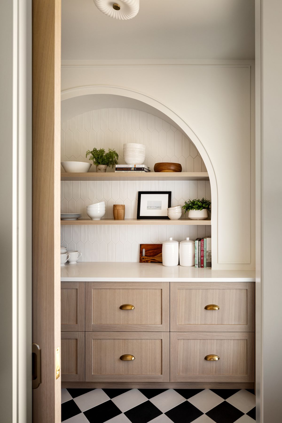 Arched pantry nook with open shelves and checkered floor