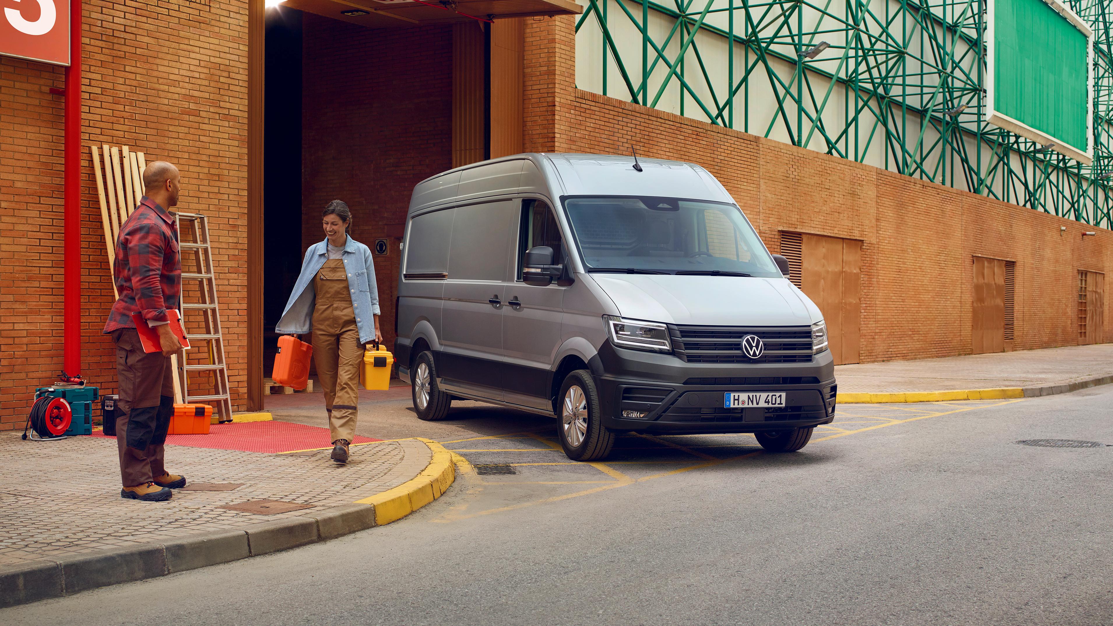Volkswagen Crafter og to stk håndtverkere som går bort fra den og bærer på materiealer