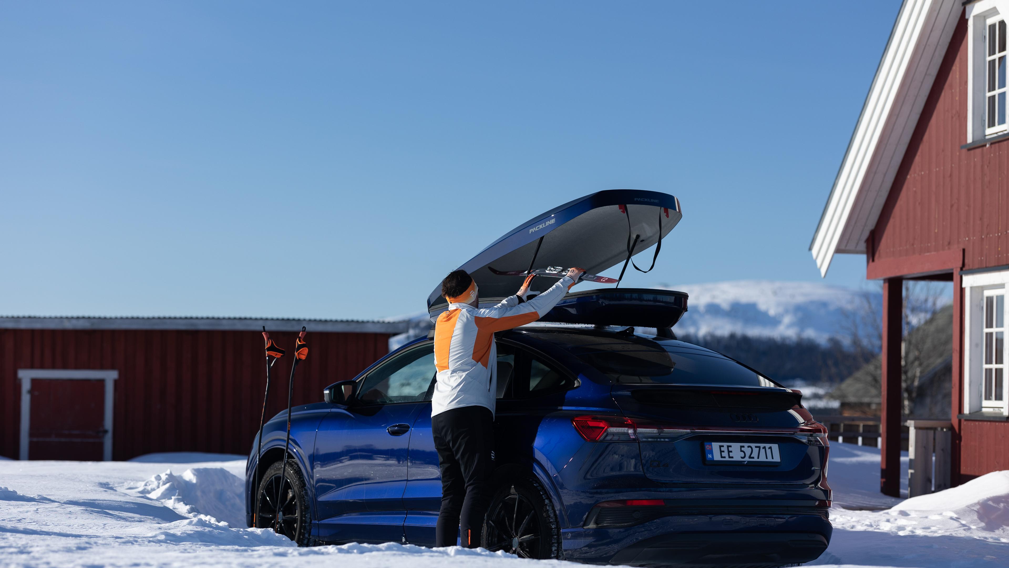 En som putter ski i en bil med takboks