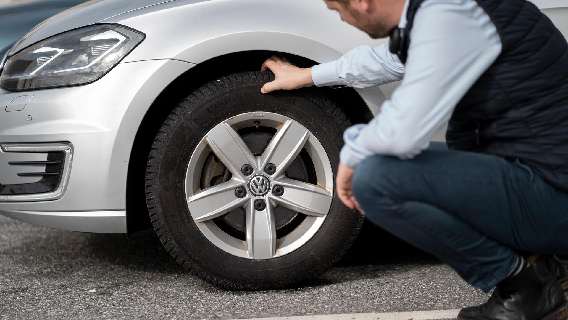 En som inspiserer dekket på en bil