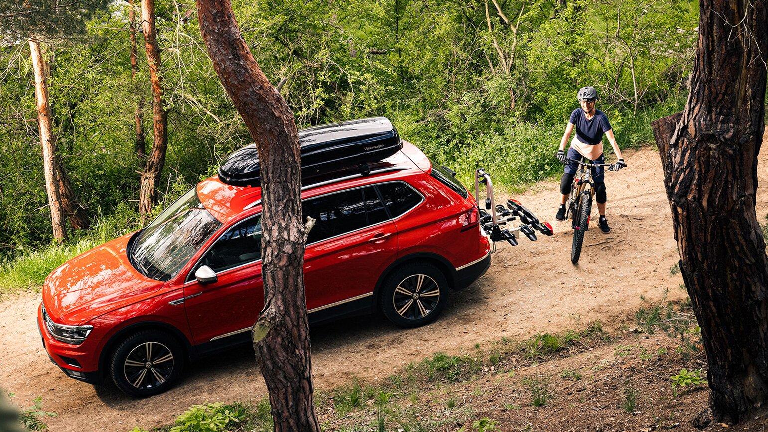 Rød Volkswagen i skogen med sykkelstativ og skiboks på taket