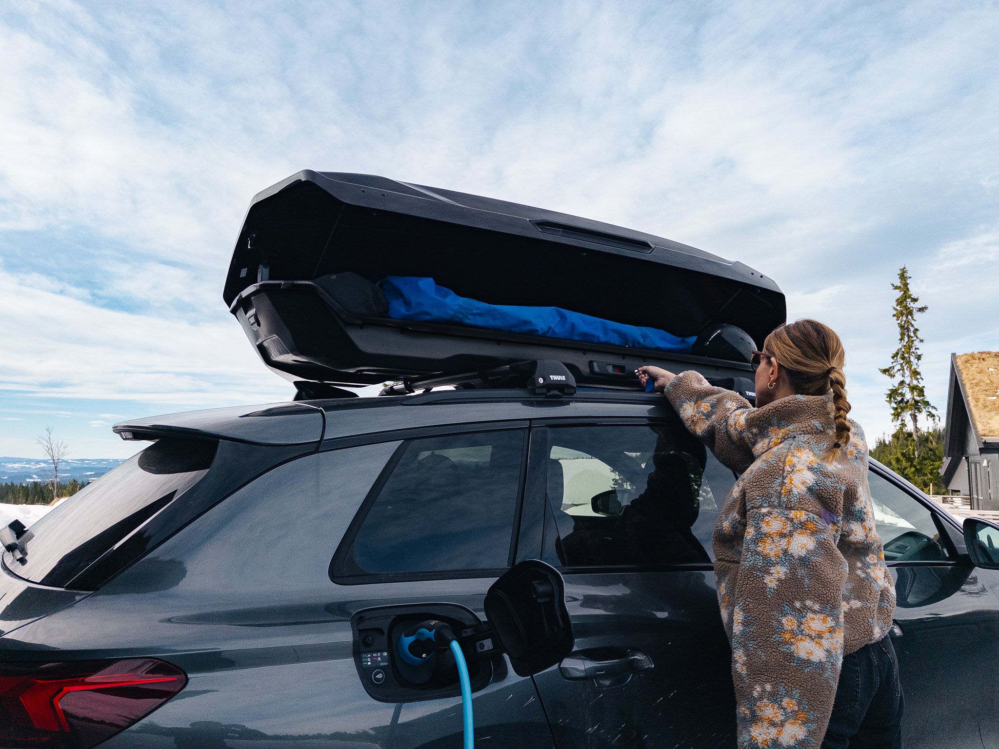 En som laster inn bagasje i skiboks på bil