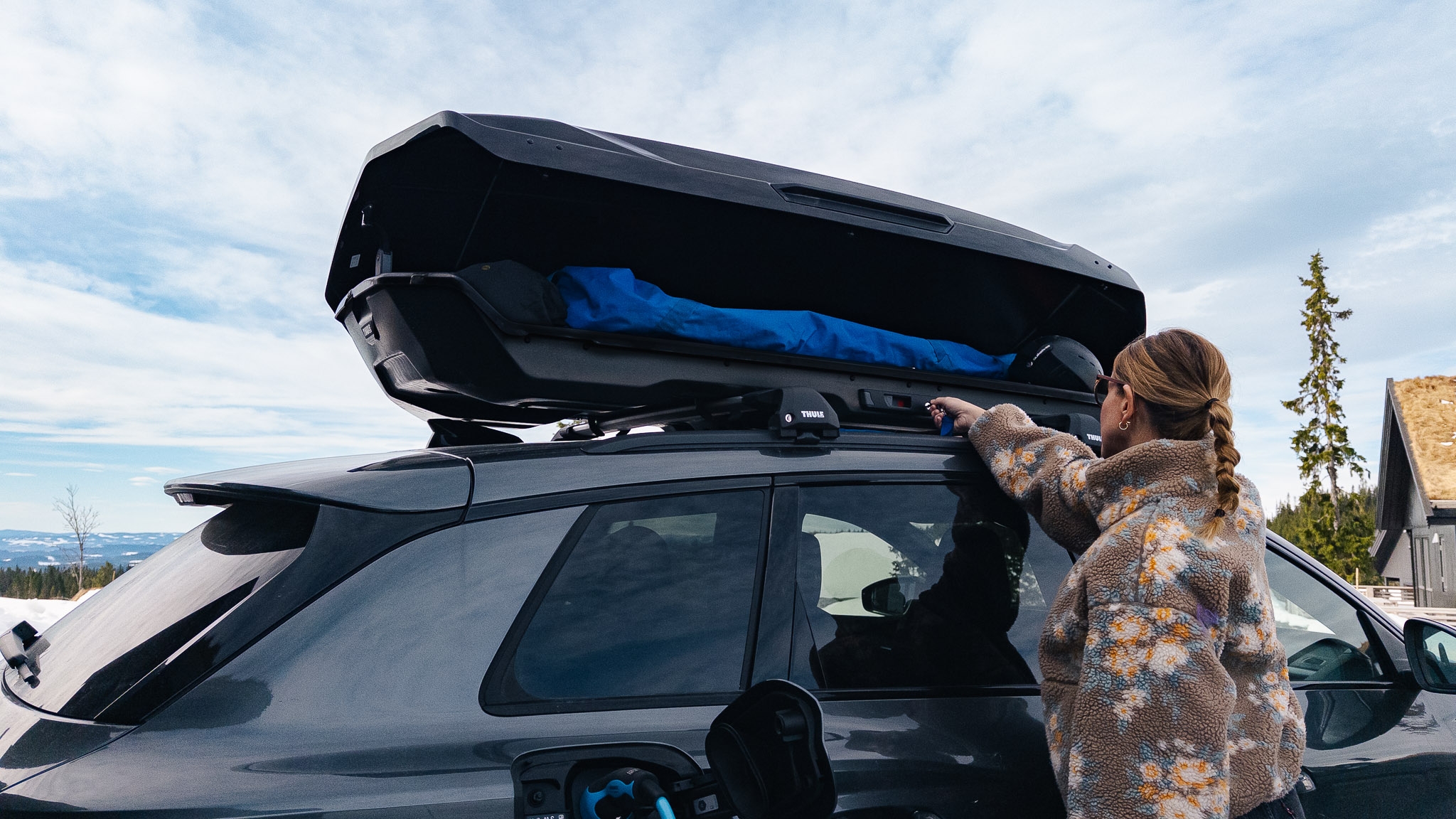 En som laster inn bagasje i skiboks på bil