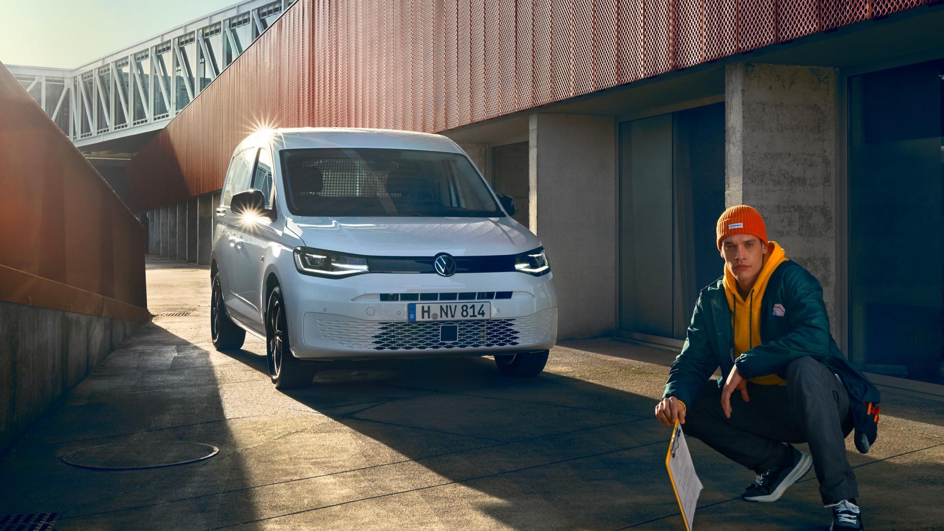 Volkswagen Caddy Cargo og to stk håndtverkere som går bort fra den og bærer på verktøy