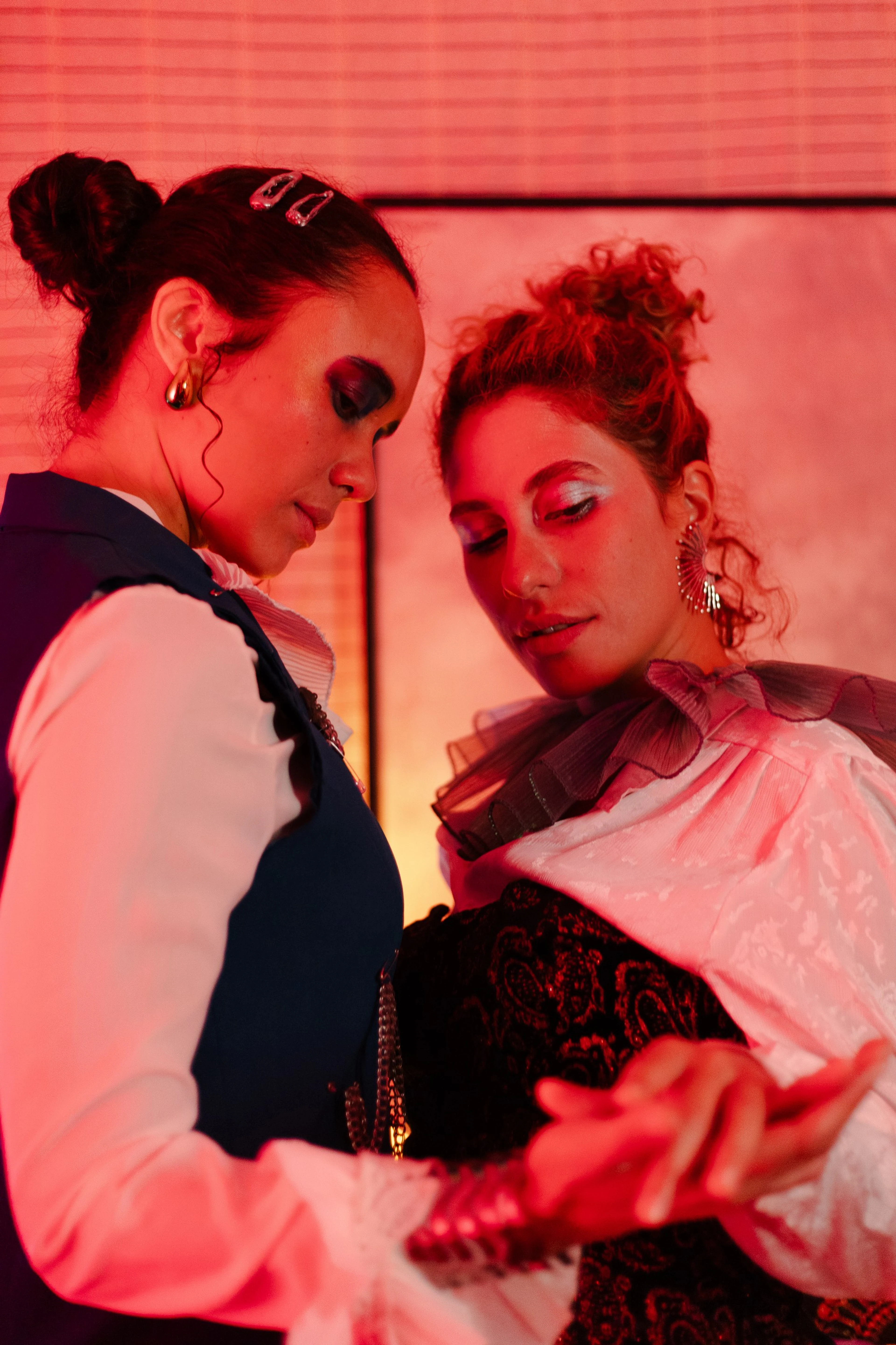 Duas atrizes com figurino de época sob luz vermelha