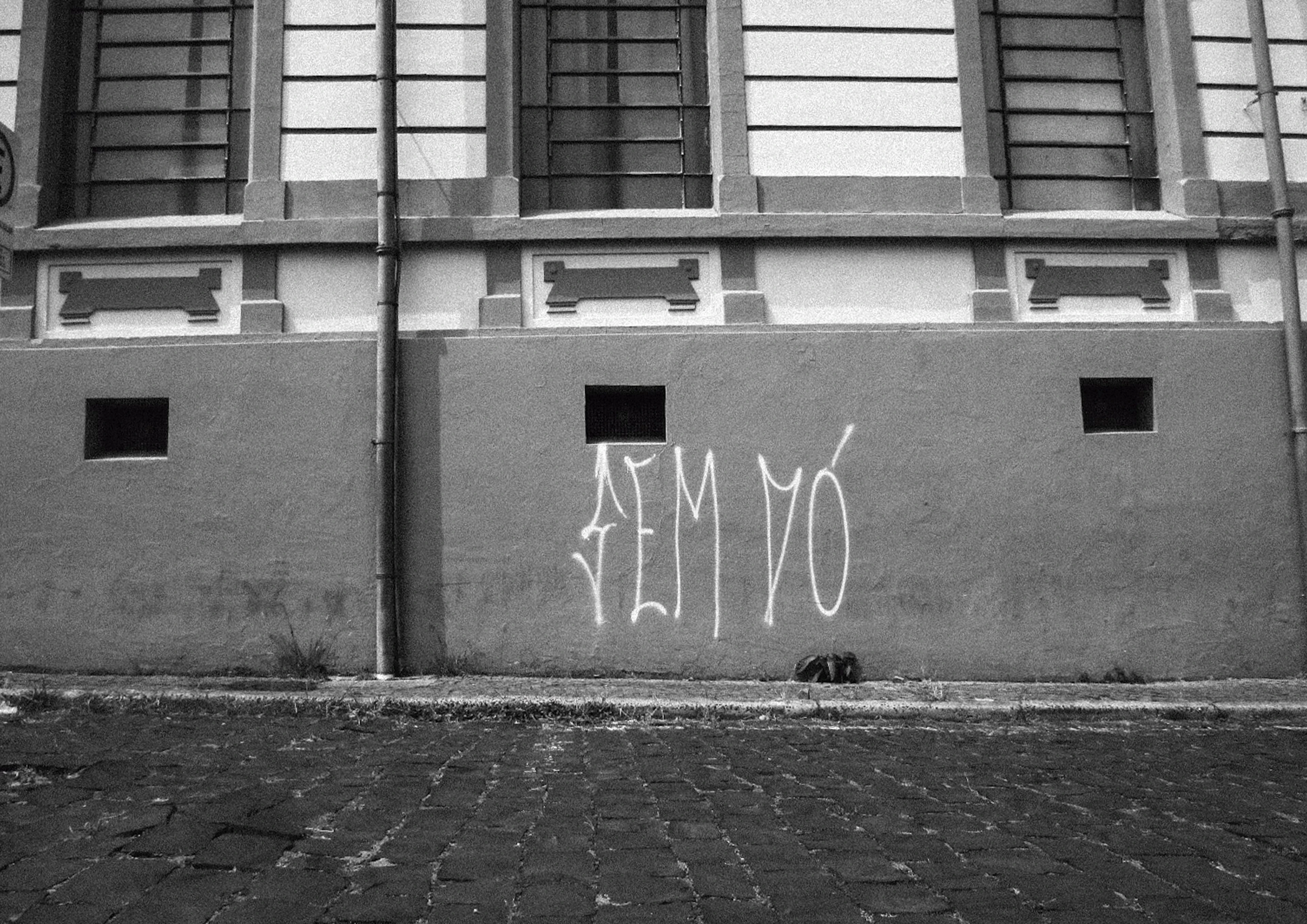 Fachada antiga com a pichação “Sem dó”, em preto e branco
