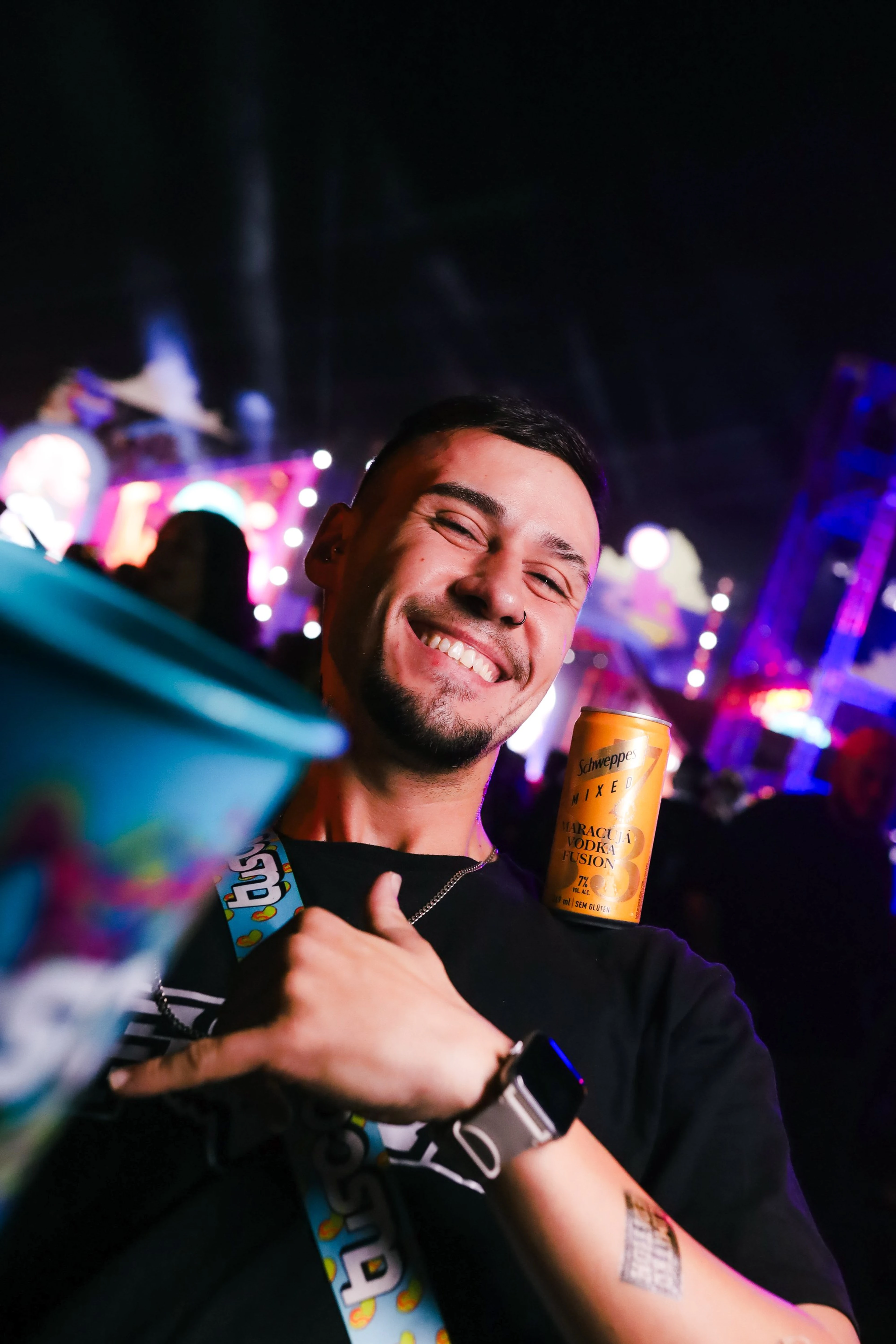 Rapaz sorrindo com uma lata na mão no meio da festa