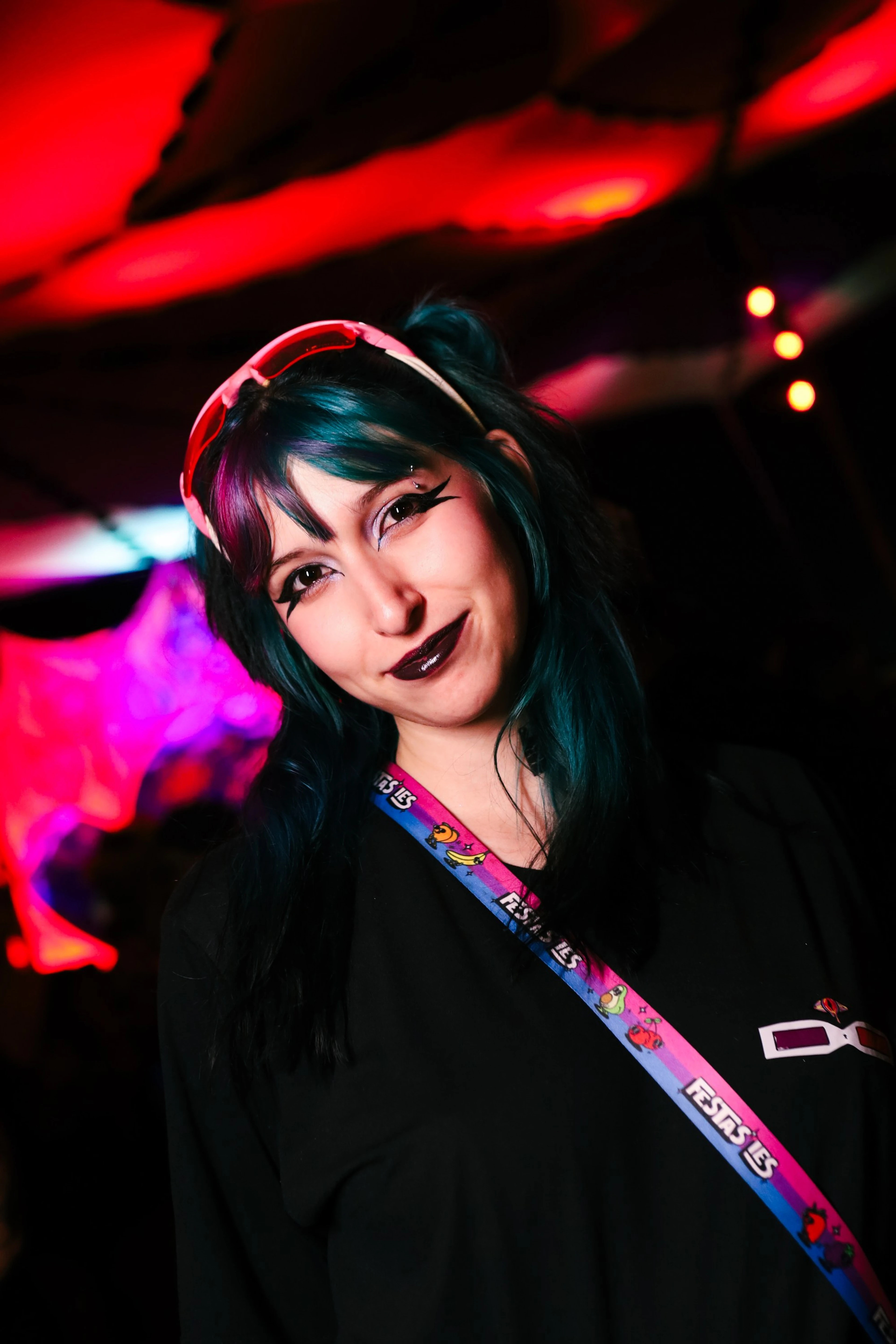 Mulher de cabelo azul com óculos rosa na cabeça sorrindo numa festa