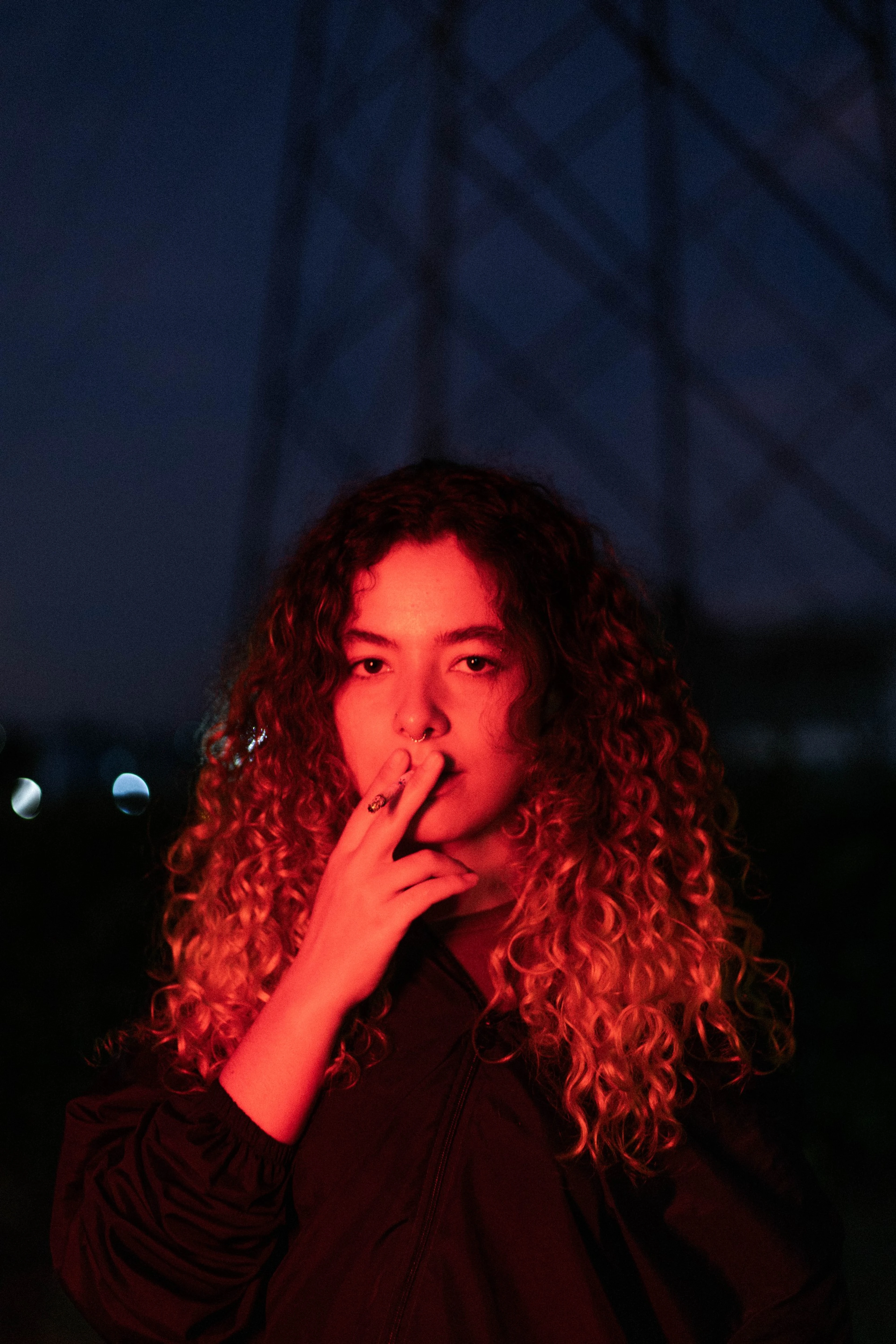 Retrato noturno de mulher de cabelo cacheado sob luz vermelha
