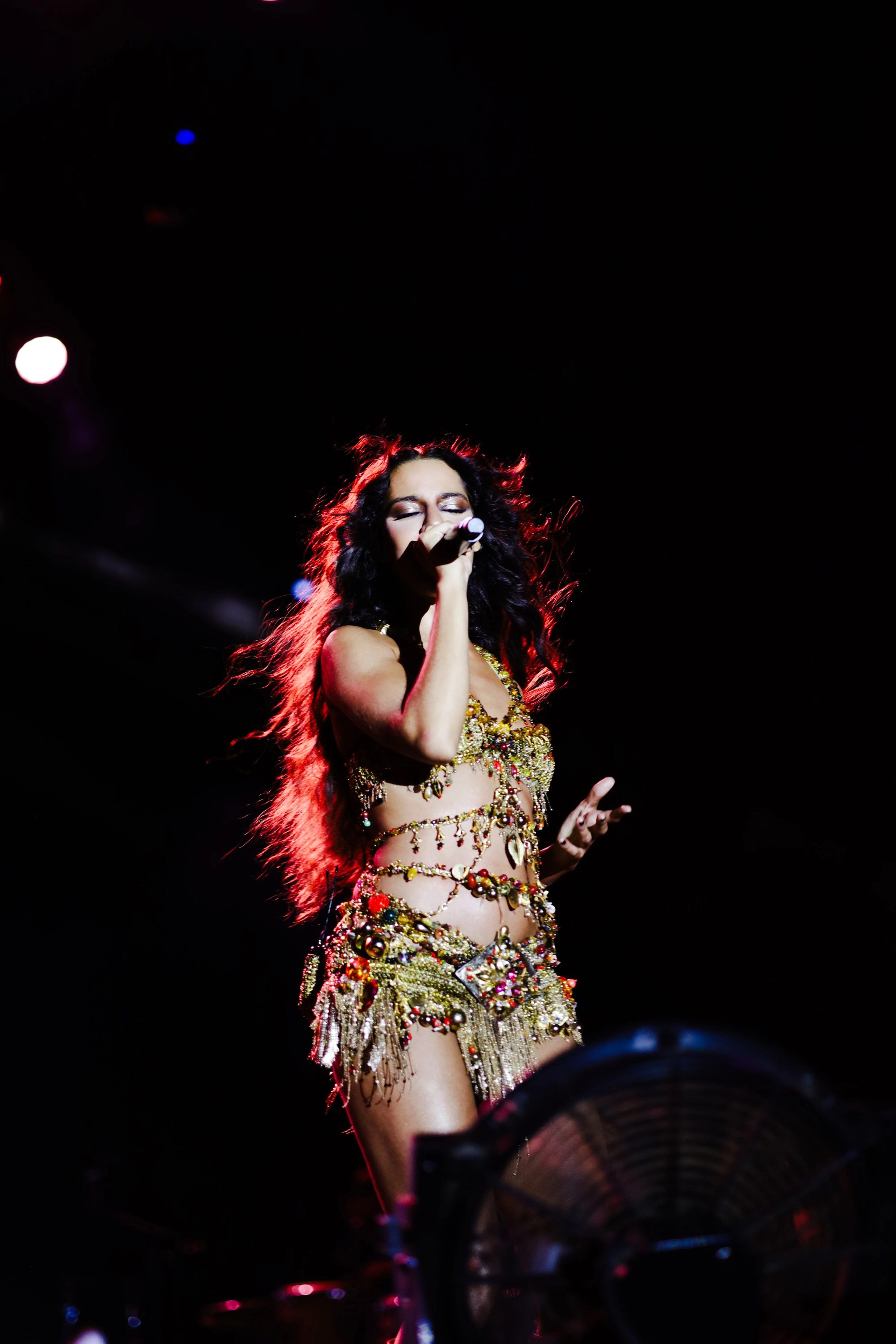 Cantora de figurino dourado cantando com o cabelo ao vento