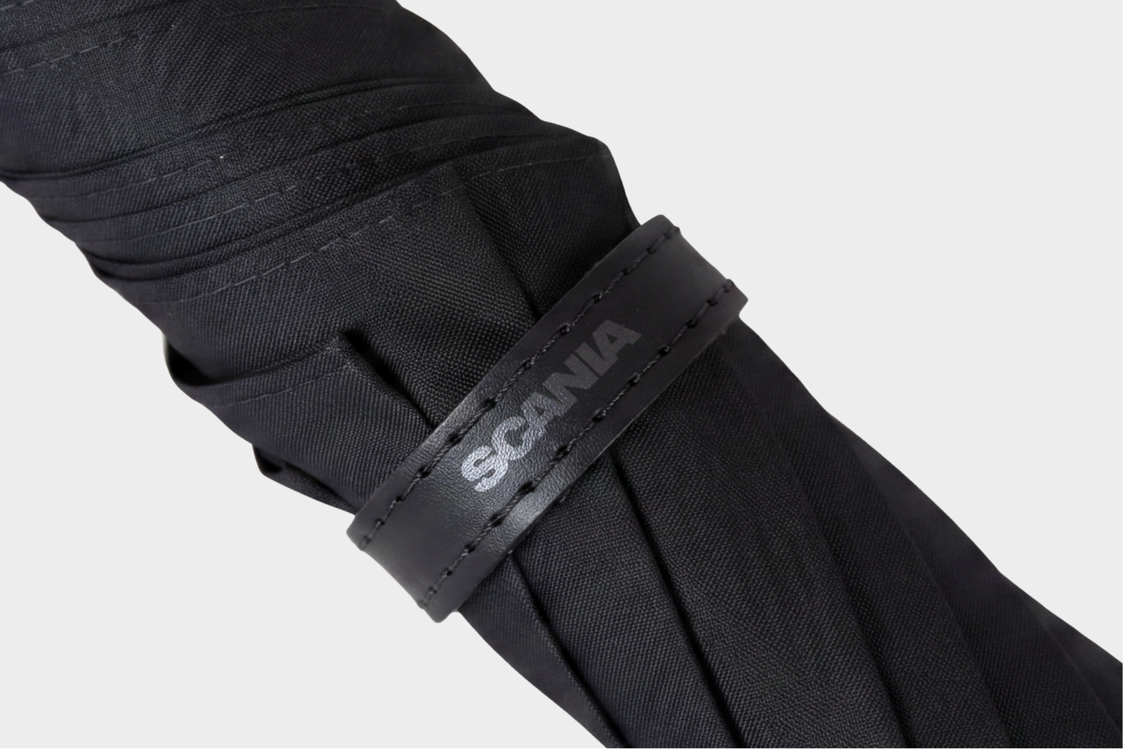 Closeup of black umbrella with Scania logotype.