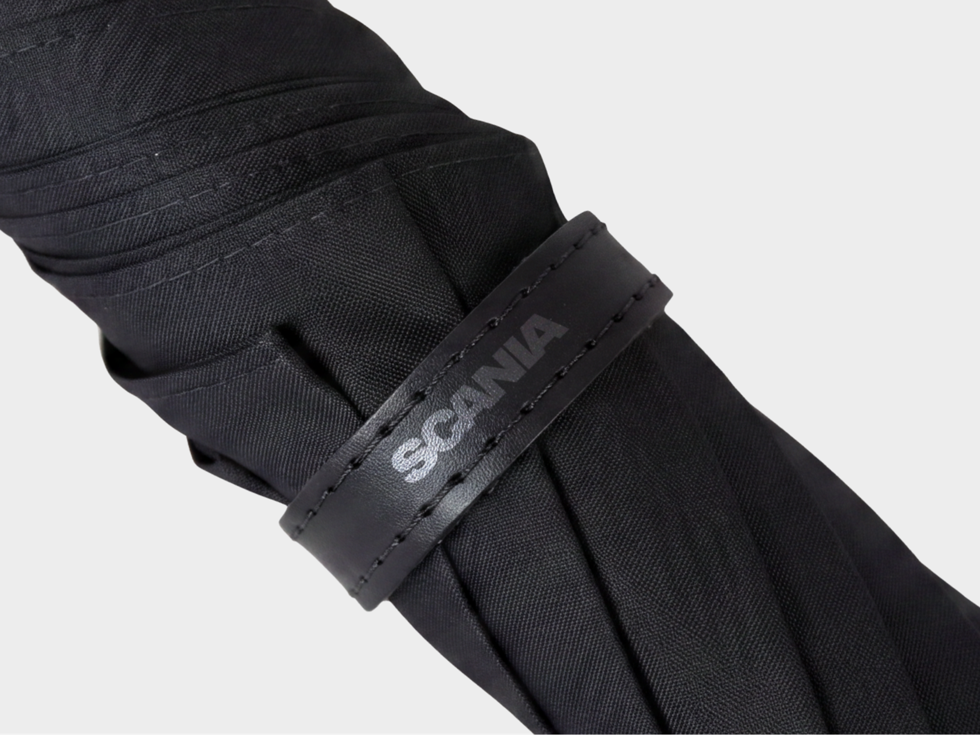 Closeup of black umbrella with Scania logotype.