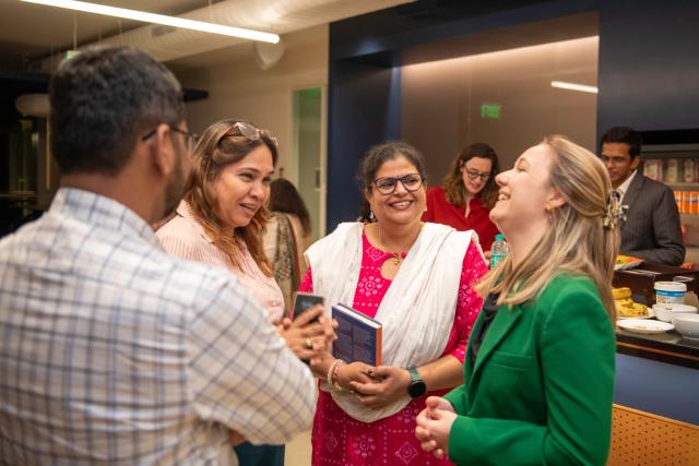 Group of attendees sharing a conversation and laughter at a book launch event