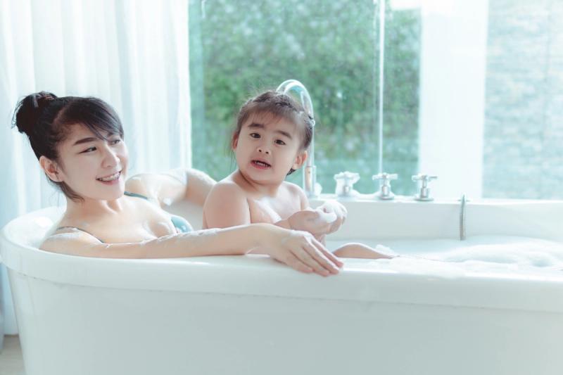 Ibu dan anak perempuan mandi bersama sambil tersenyum, momen kedekatan orang tua dan anak