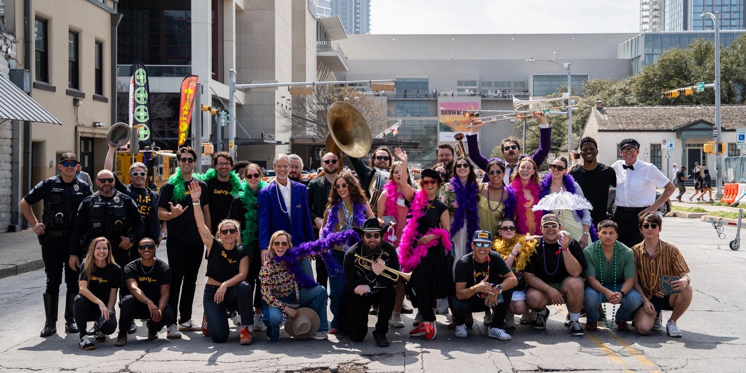 A large group of people in festive costumes, some holding musical instruments, and police officers pose on a city street.