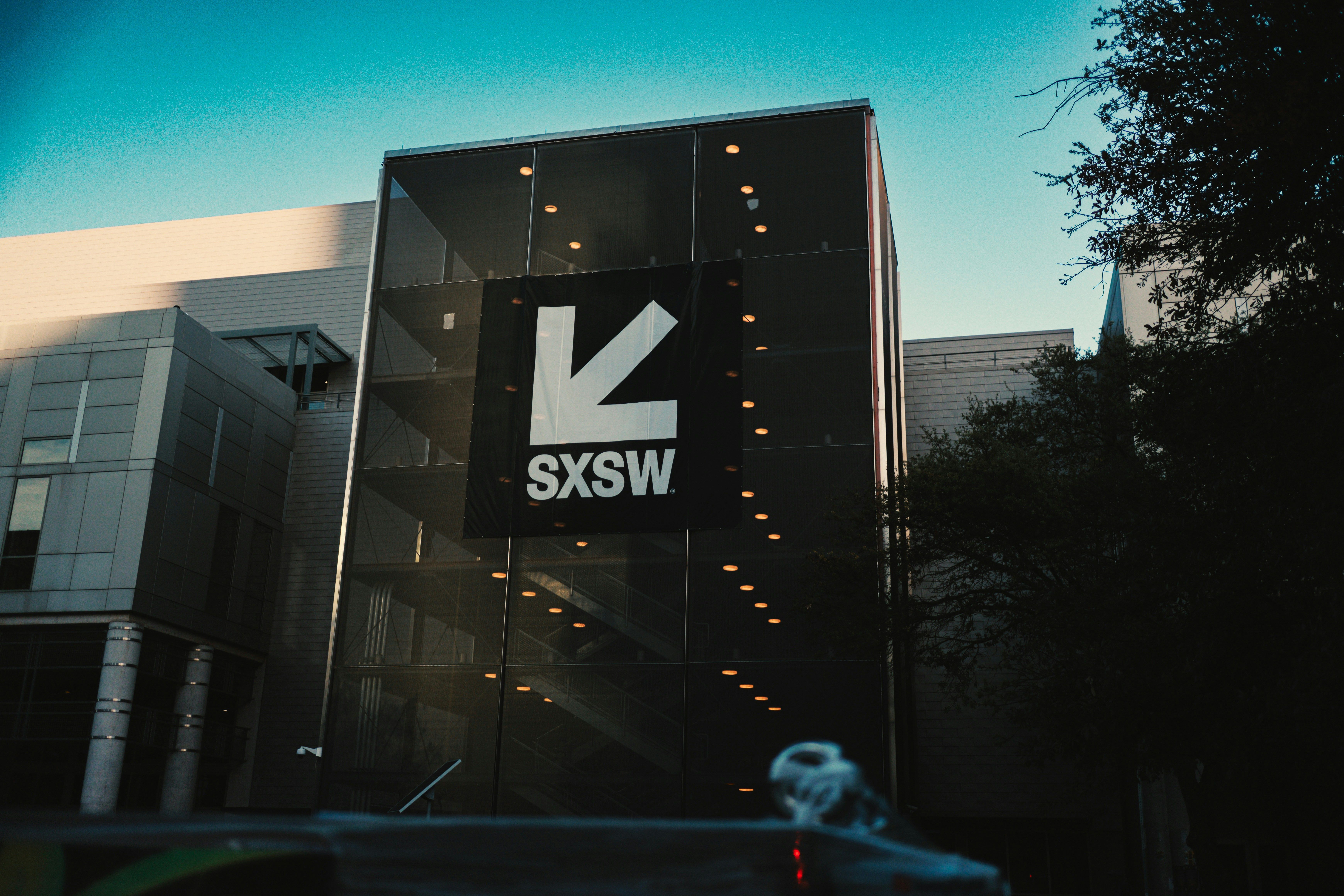 A modern glass building prominently displays a white SXSW logo and arrow.​​​​‌﻿‍﻿​‍​‍‌‍﻿﻿‌﻿​‍‌‍‍‌‌‍‌﻿‌‍‍‌‌‍﻿‍​‍​‍​﻿‍‍​‍​‍‌﻿​﻿‌‍​‌‌‍﻿‍‌‍‍‌‌﻿‌​‌﻿‍‌​‍﻿‍‌‍‍‌‌‍﻿﻿​‍​‍​‍﻿​​‍​‍‌‍‍​‌﻿​‍‌‍‌‌‌‍‌‍​‍​‍​﻿‍‍​‍​‍​‍﻿﻿‌﻿​﻿‌﻿‌​‌﻿‌‌‌‍‌​‌‍‍‌‌‍﻿﻿​‍﻿﻿‌‍‍‌‌‍﻿‍‌﻿‌​‌‍‌‌‌‍﻿‍‌﻿‌​​‍﻿﻿‌‍‌‌‌‍‌​‌‍‍‌‌﻿‌​​‍﻿﻿‌‍﻿‌‌‍﻿﻿‌‍‌​‌‍‌‌​﻿﻿‌‌﻿​​‌﻿​‍‌‍‌‌‌﻿​﻿‌‍‌‌‌‍﻿‍‌﻿‌​‌‍​‌‌﻿‌​‌‍‍‌‌‍﻿﻿‌‍﻿‍​﻿‍﻿‌‍‍‌‌‍‌​​﻿﻿‌​﻿‌‍​﻿‌‌​﻿‌‍​﻿​‍​﻿‌​​﻿​​‌‍​‍​﻿​﻿​‍﻿‌​﻿​﻿​﻿​​‌‍​‍​﻿‌​​‍﻿‌​﻿‌​​﻿‌‌​﻿​‌​﻿‌﻿​‍﻿‌​﻿‍​‌‍‌‍​﻿‌‍​﻿​‌​‍﻿‌‌‍‌‌‌‍‌‍​﻿‌‌​﻿‌﻿​﻿‌​​﻿​‍​﻿‌﻿​﻿‌‍‌‍‌​​﻿‌‍​﻿‌‍​﻿‌​​﻿‍﻿‌﻿‌​‌﻿‍‌‌﻿​​‌‍‌‌​﻿﻿‌‌﻿​​‌‍﻿﻿‌﻿​﻿‌﻿‌​​﻿‍﻿‌﻿​​‌‍​‌‌﻿‌​‌‍‍​​﻿﻿‌‌‍​﻿‌‍﻿﻿‌﻿‌‍‌‍‌‌‌﻿​‍‌​‍‌‌‍﻿‌‌‍​‌‌‍‌﻿‌‍‌‌​‍﻿‍‌‍​‌‌‍﻿​‌﻿‌​​﻿﻿﻿‌‍​‍‌‍​‌‌﻿​﻿‌‍‌‌‌‌‌‌‌﻿​‍‌‍﻿​​﻿﻿‌​‍‌‌​﻿​‍‌​‌‍‌﻿​﻿‌﻿‌​‌﻿‌‌‌‍‌​‌‍‍‌‌‍﻿﻿​‍‌‍‌‍‍‌‌‍‌​​﻿﻿‌​﻿‌‍​﻿‌‌​﻿‌‍​﻿​‍​﻿‌​​﻿​​‌‍​‍​﻿​﻿​‍﻿‌​﻿​﻿​﻿​​‌‍​‍​﻿‌​​‍﻿‌​﻿‌​​﻿‌‌​﻿​‌​﻿‌﻿​‍﻿‌​﻿‍​‌‍‌‍​﻿‌‍​﻿​‌​‍﻿‌‌‍‌‌‌‍‌‍​﻿‌‌​﻿‌﻿​﻿‌​​﻿​‍​﻿‌﻿​﻿‌‍‌‍‌​​﻿‌‍​﻿‌‍​﻿‌​​‍‌‍‌﻿‌​‌﻿‍‌‌﻿​​‌‍‌‌​﻿﻿‌‌﻿​​‌‍﻿﻿‌﻿​﻿‌﻿‌​​‍‌‍‌﻿​​‌‍​‌‌﻿‌​‌‍‍​​﻿﻿‌‌‍​﻿‌‍﻿﻿‌﻿‌‍‌‍‌‌‌﻿​‍‌​‍‌‌‍﻿‌‌‍​‌‌‍‌﻿‌‍‌‌​‍﻿‍‌‍​‌‌‍﻿​‌﻿‌​​‍‌‍‌﻿​​‌‍‌‌‌﻿​‍‌﻿​﻿‌﻿​​‌‍‌‌‌‍​﻿‌﻿‌​‌‍‍‌‌﻿‌‍‌‍‌‌​﻿﻿‌‌﻿​​‌﻿‌‌‌‍​‍‌‍﻿​‌‍‍‌‌﻿​﻿‌‍‍​‌‍‌‌‌‍‌​​‍​‍‌﻿﻿‌