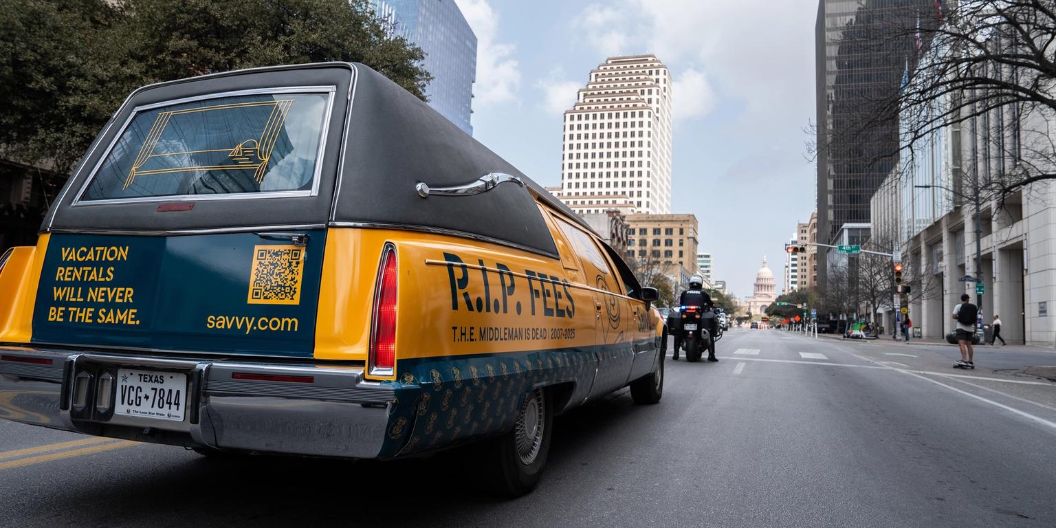a yellow and blue coffin is driving down a city street .