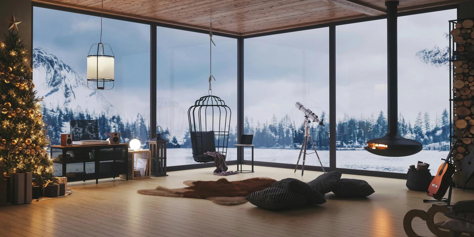 Modern room with a Christmas tree, hanging fireplace, and large windows revealing a snowy mountain scene.