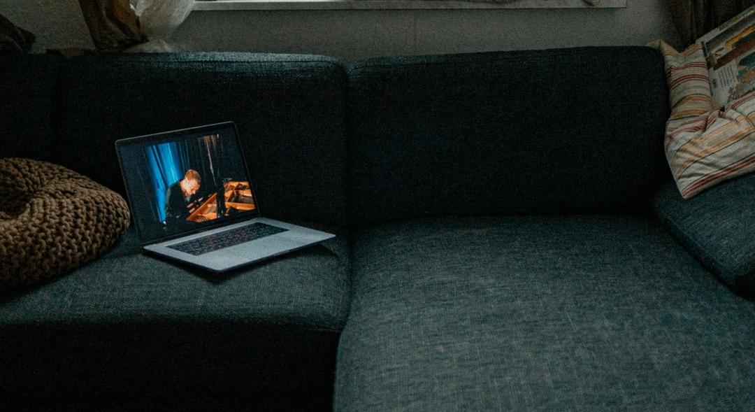 Laptop on a gray couch in a dimly lit living room