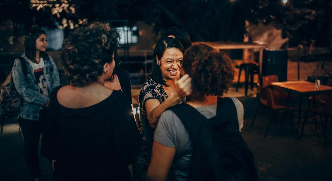 Woman having friendly conversation with two other women.