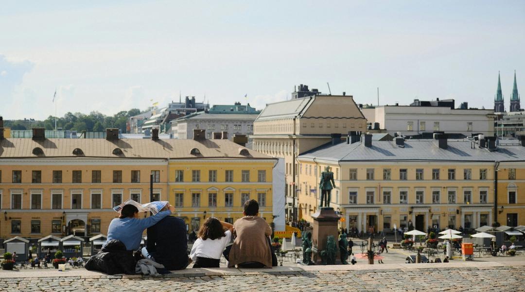 A group of people sitting on a wall overlooking a European city.