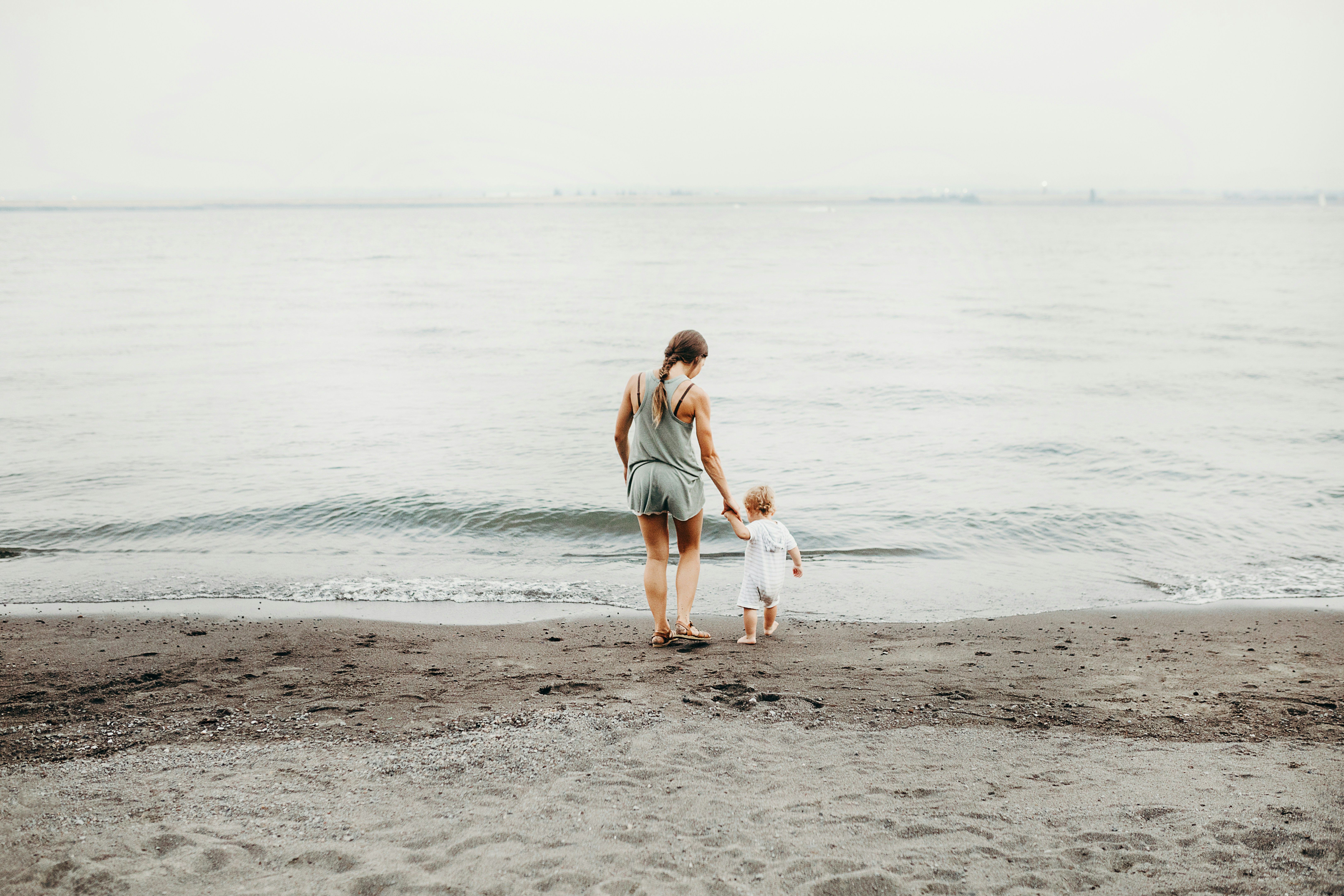 Woman and a baby walking on the beach.