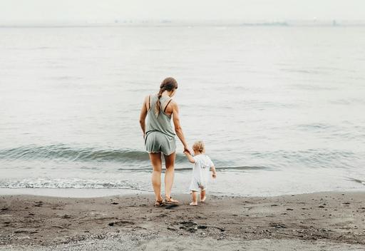 Woman and a baby walking on the beach.