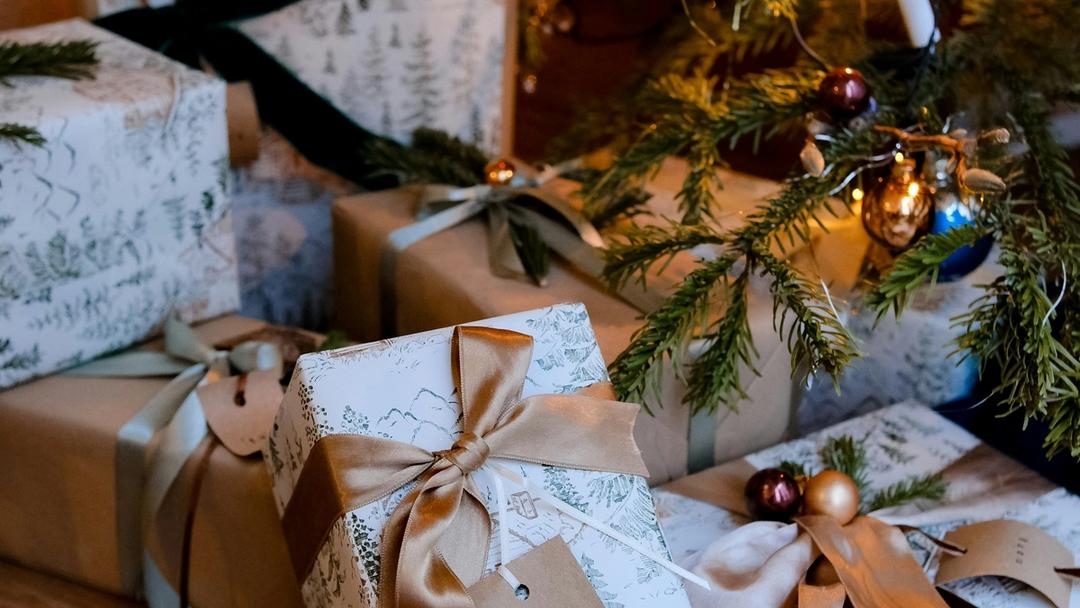 Wrapped presents sitting under a christmas tree.