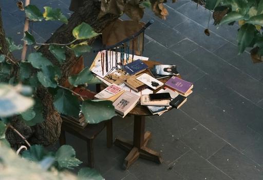 Books lying on a wooden table outside.
