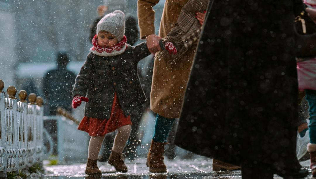 Woman holding child's hand in the snow.