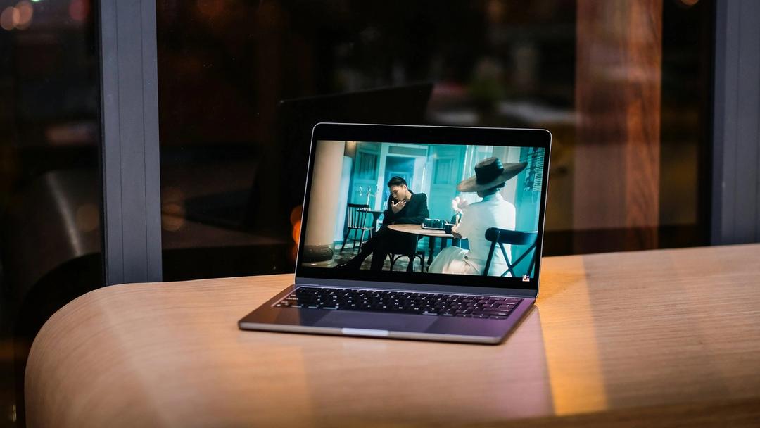 A laptop displaying a video lying on a table.