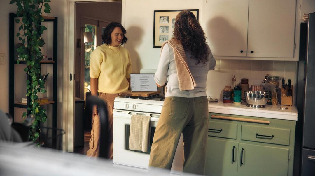 Two women talking in the kitchen while cooking.