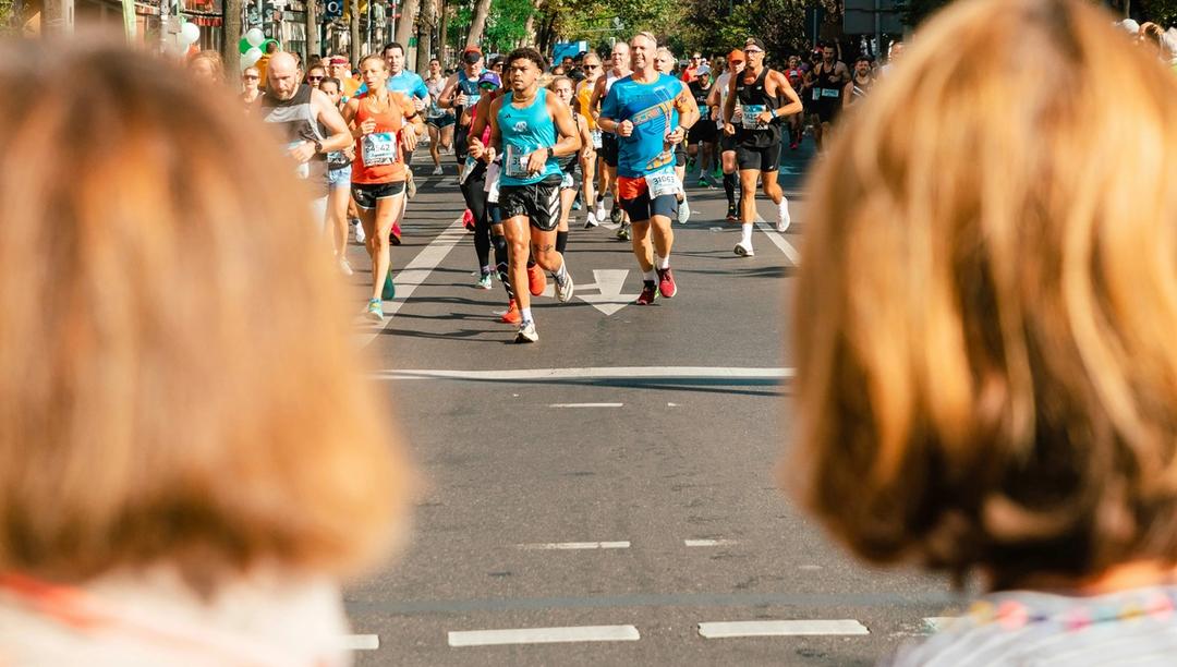 Two women watching a group of people running in an event.