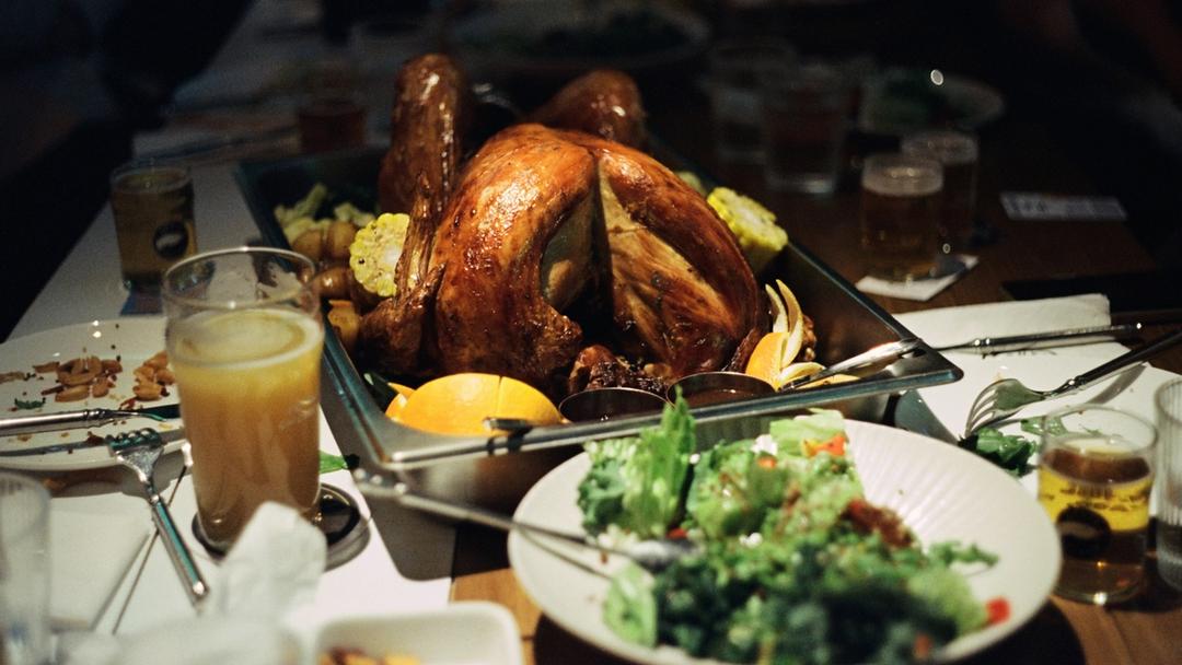 A table filled with plates and a cooked turkey.