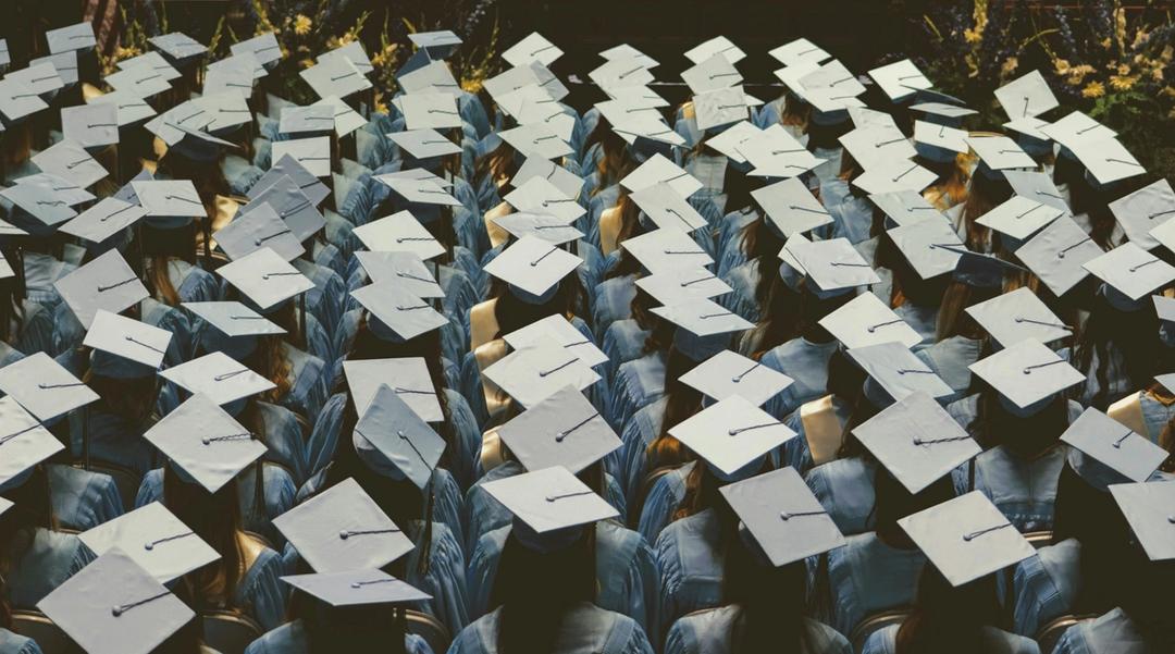 Graduates in caps and gowns seated during a commencement ceremony.