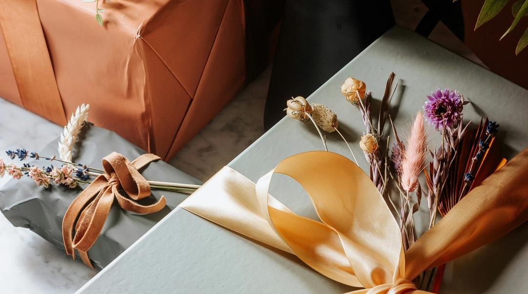 Wrapped gift boxes decorated with ribbons and flowers on a table.