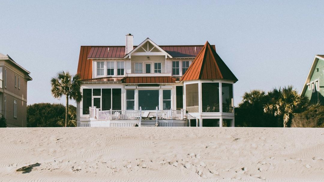 A brown and white house in front of the beach.