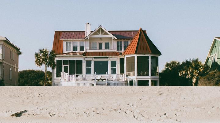 A brown and white house in front of the beach.