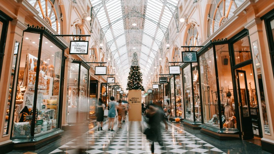 People walking in an indoor shopping mall with a christmas tree inside.