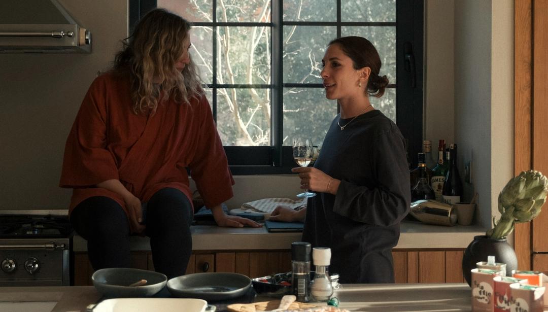 Two people chatting in a sunlit kitchen.
