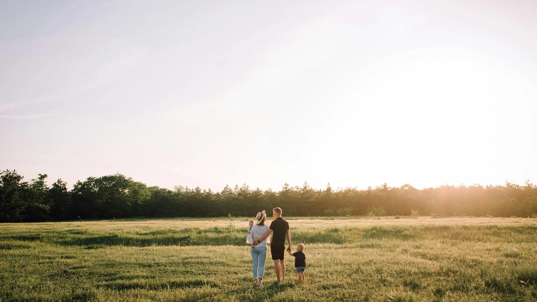 A family holding hands outside.