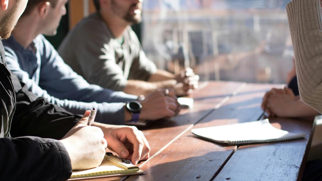 People sitting at a table with note paper in front of them.