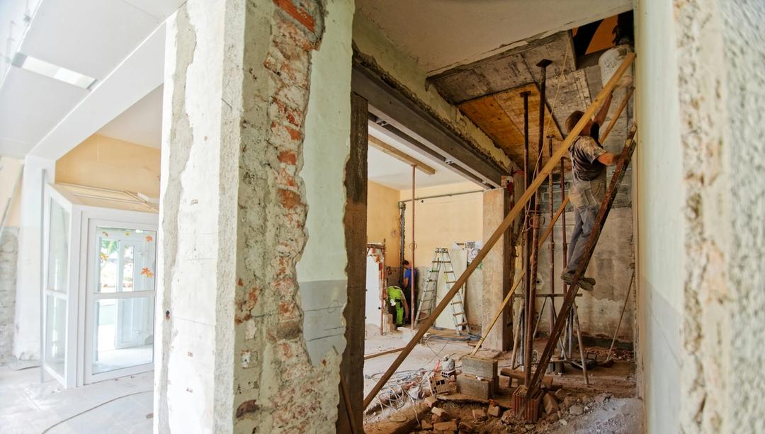 Man climbing ladder in house during renovation.