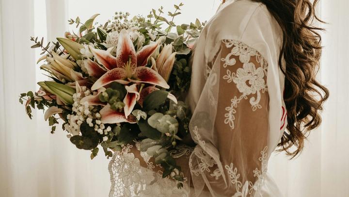 Woman in white holding a bouquet of flowers.