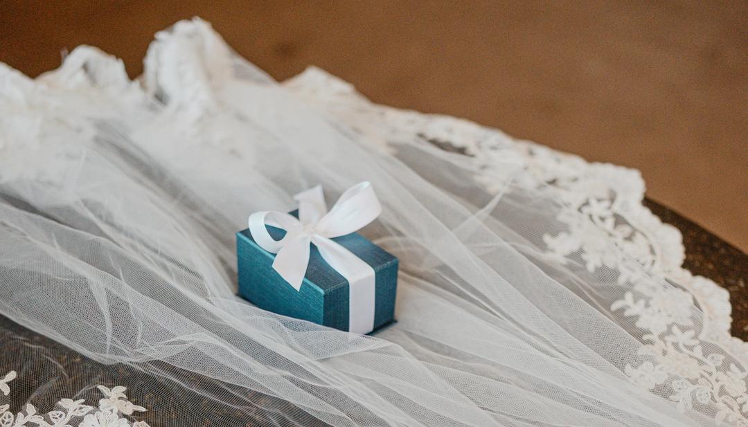 A white wedding veil with a small blue gift box on top.