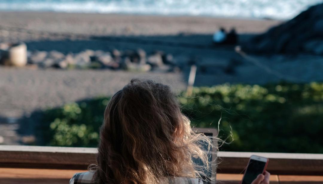 A woman working on her computer overlooking the ocean.