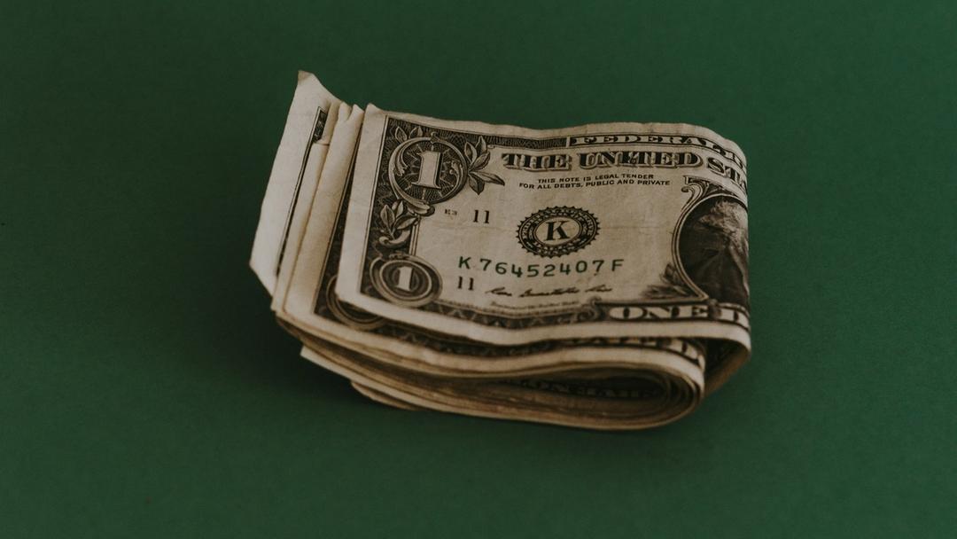 A little wad of cash sitting on a green surface.