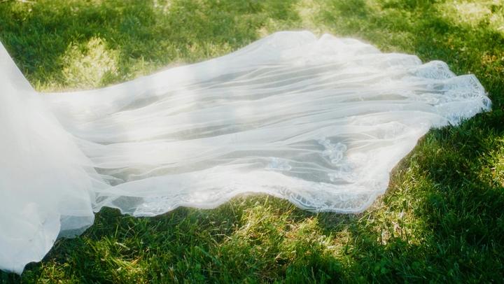 A wedding dress laying on the grass.